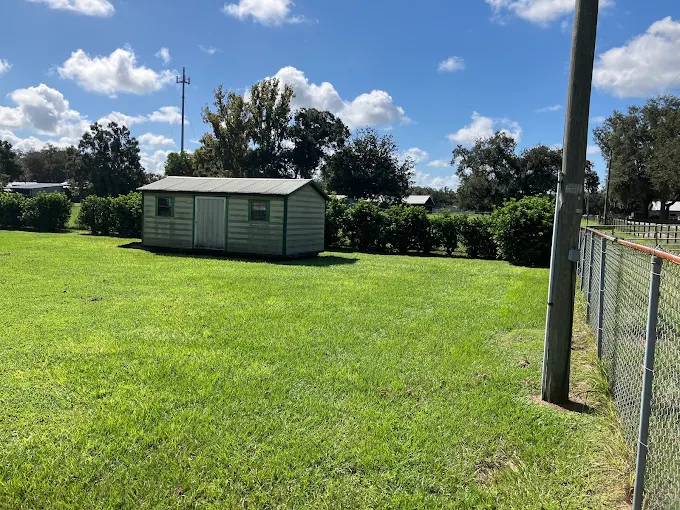 Wide open acreage lawn mowed clean around a shed